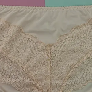 Détail macro montrant le motif de dentelle florale sur cette culotte sans couture de couleur crème