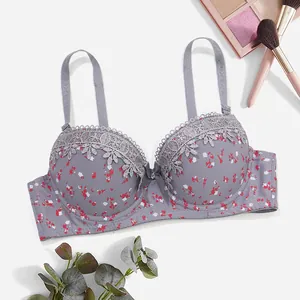 Detalle de sujetador gris con estampado floral, bordado de encaje y lazo central.