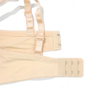 Primer plano de sujetador beige con tirantes ajustables y cierre de 3 filas de corchetes.
