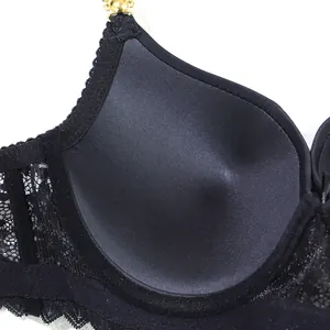 Close-up detail of a black lace bra cup featuring a golden metal chain strap attachment.