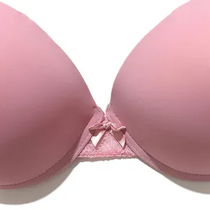 Macro detail of smooth pink push-up bra featuring a center bow and elegant lace trim
