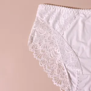 Nahaufnahme weißer floraler Spitzendetails an weicher Damenunterwäsche mit mittlerer Taille