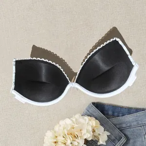 Close-up of black satin push-up bra cups with white lace trim for party dresses