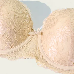 Detailopname van een beige kanten balconette bh met bloemenpatroon en een klein strikje