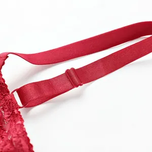 Macro view showing the adjustable red elastic shoulder strap of a floral lace bra