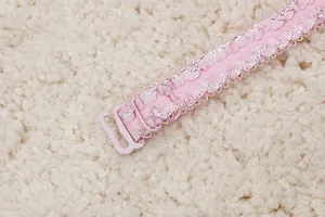 Gros plan d'une bretelle de soutien-gorge en dentelle rose avec fil métallisé et crochet.
