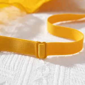 Detailed view of adjustable vibrant yellow lace bra shoulder strap with plastic slider buckle