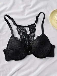 Close-up detail of a black lace front-closure bra with an intricate floral racerback design