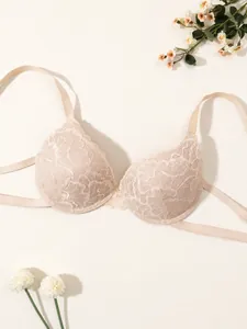 Primo piano di un elegante reggiseno in pizzo beige con motivi floreali