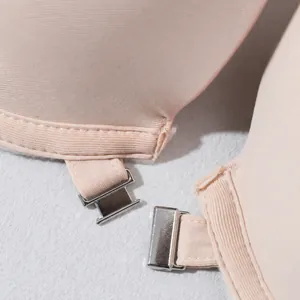 Makro-Detail des silbernen Frontverschlusses an einem beigen Push-up-BH aus Stoff
