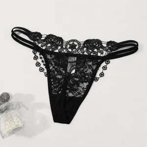 Vue détaillée d'un string en dentelle noire avec broderie florale et fines lanières
