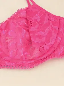 Gros plan sur la texture complexe de la dentelle rose vif d'un bonnet de soutien-gorge