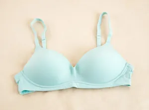 Dettaglio di un reggiseno push-up senza cuciture verde menta su sfondo in tessuto neutro