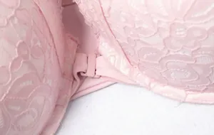 Dettaglio macro della chiusura frontale e del pizzo floreale su un reggiseno rosa