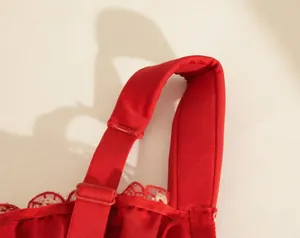 Primer plano de tirante ancho de sujetador rojo con bordado y hebilla ajustable.