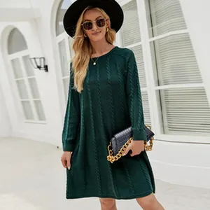 Model wearing loose emerald green cable-knit sweater dress in an urban outdoor setting