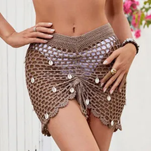 Close-up detail of brown crochet beach mini skirt with decorative white shell charms