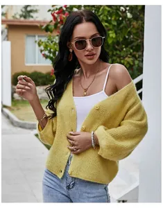 Detailed view of a yellow V-neck knit cardigan styled with a white top and jeans.