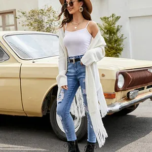Détail d'un cardigan blanc en maille à franges porté par un mannequin près d'une voiture