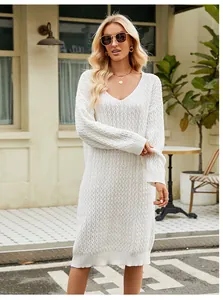 Detailed shot of a white V-neck cable knit sweater dress worn by a model in an urban setting.