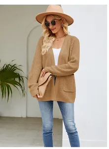 Modische Frau in camelfarbener Strickjacke mit Waffelmuster im klassischen Outdoor-Lifestyle.