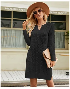 Cable-knit black midi sweater dress styled with a hat and clutch in an outdoor cafe.