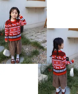 Detailed view of child wearing red knit Christmas sweater with reindeer patterns