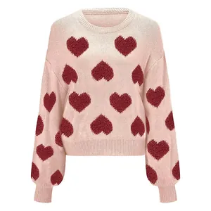 Detail view of pink knitted sweater with red heart jacquard patterns and puff sleeves.