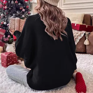 Vista posteriore di un maglione nero a maniche a pipistrello in un accogliente set natalizio