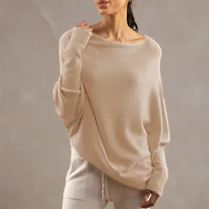 Detail view of a beige boat neck knitted sweater with batwing sleeves and soft texture.