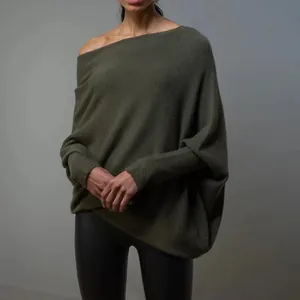 Model wearing an oversized dark olive green off-the-shoulder knit sweater with batwing sleeves.