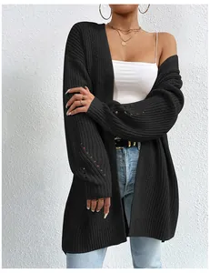 Dettaglio del cardigan in maglia nera oversize da donna su sfondo di muro testurizzato