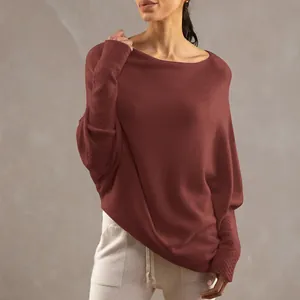 Detail of loose boat neck knit pullover with batwing sleeves in terracotta color