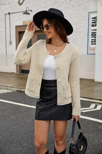Elegant model in een beige gebreid vest met parelknopen en een zwarte leren rok in stad.