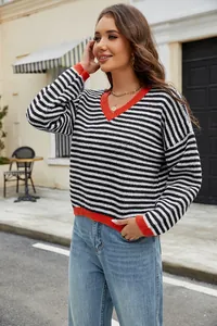 Fashionable V-neck striped knit sweater with orange trim on casual street background