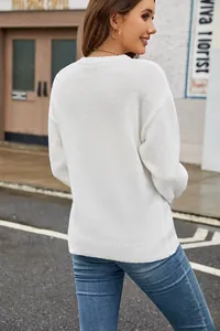 Back view of a classic white crewneck knit sweater presented in a stylish street setting