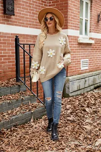 Detail view of women's loose knit sweater with 3D white crochet daisy flowers