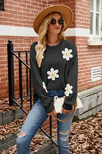 Close-up detail of black knit sweater featuring decorative white 3D crochet flowers.