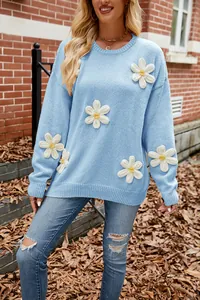 Detail view of a light blue crew neck sweater featuring 3D white crochet flower appliques.
