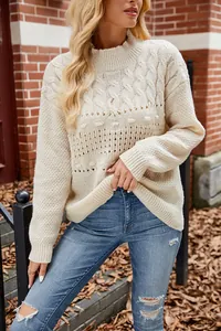 Detail of a beige cable-knit sweater with patterned stitching and a relaxed fit