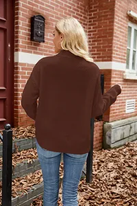 Back view of brown waffle knit sweater on model in an autumn outdoor brick wall setting