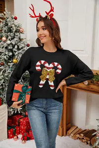 Dettaglio di un maglione natalizio nero da donna con bastoncino di zucchero e fiocco in paillettes