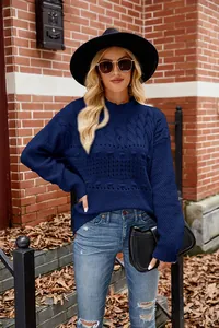 Detail of navy blue cable knit sweater worn by model in urban street setting