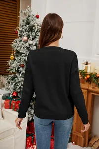 Vista posteriore di un maglione natalizio nero da donna in un accogliente ambiente festivo