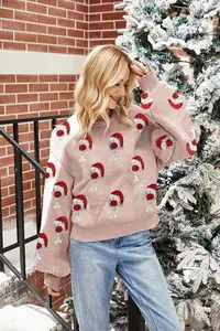 Cozy pink oversized Christmas sweater with festive Santa hat patterns and bubble sleeves.