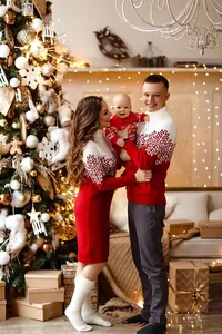 Famiglia con maglioni natalizi rossi e motivi a fiocchi di neve in una stanza festiva