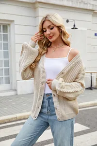 Detailed shot of beige chunky knit cardigan with twist patterns and amber buttons