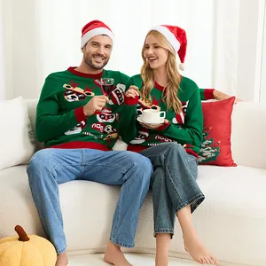 Pareja con suéteres verdes de renos navideños sentada en un sofá blanco.