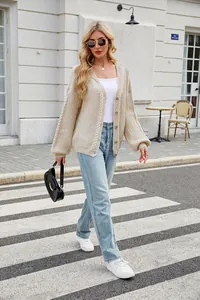 Street style view of an oversized cream cable knit cardigan featuring a V-neck design.