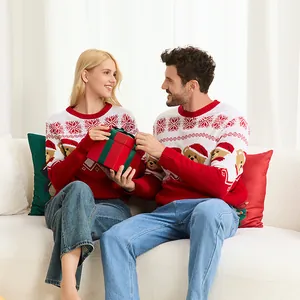 Pareja feliz con suéteres navideños rojos a juego con jacquard de oso en el sofá.
